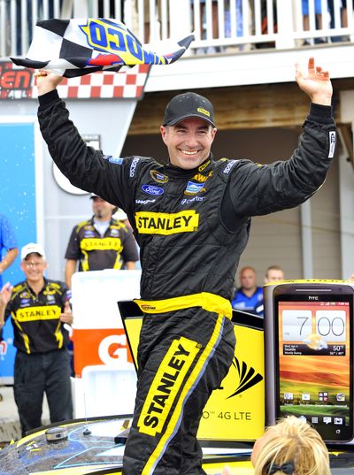 Marcos Ambrose celebrates on top of his car in victory lane. (Associated Press)