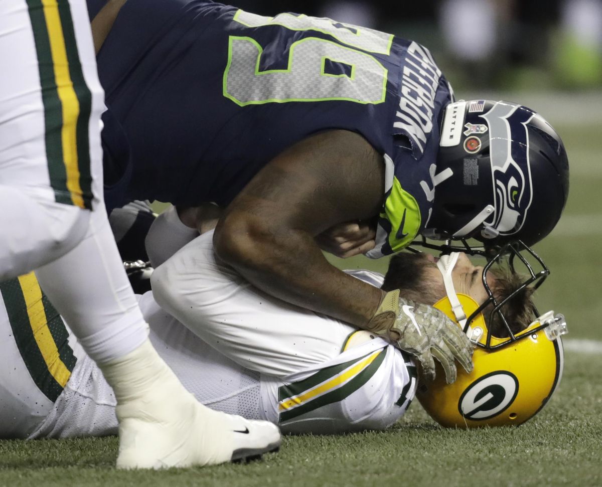 Green Bay Packers quarterback Aaron Rodgers, bottom, is sacked by defensive end Quinton Jefferson, top, during the first half Thursday in Seattle. (Stephen Brashear / AP)
