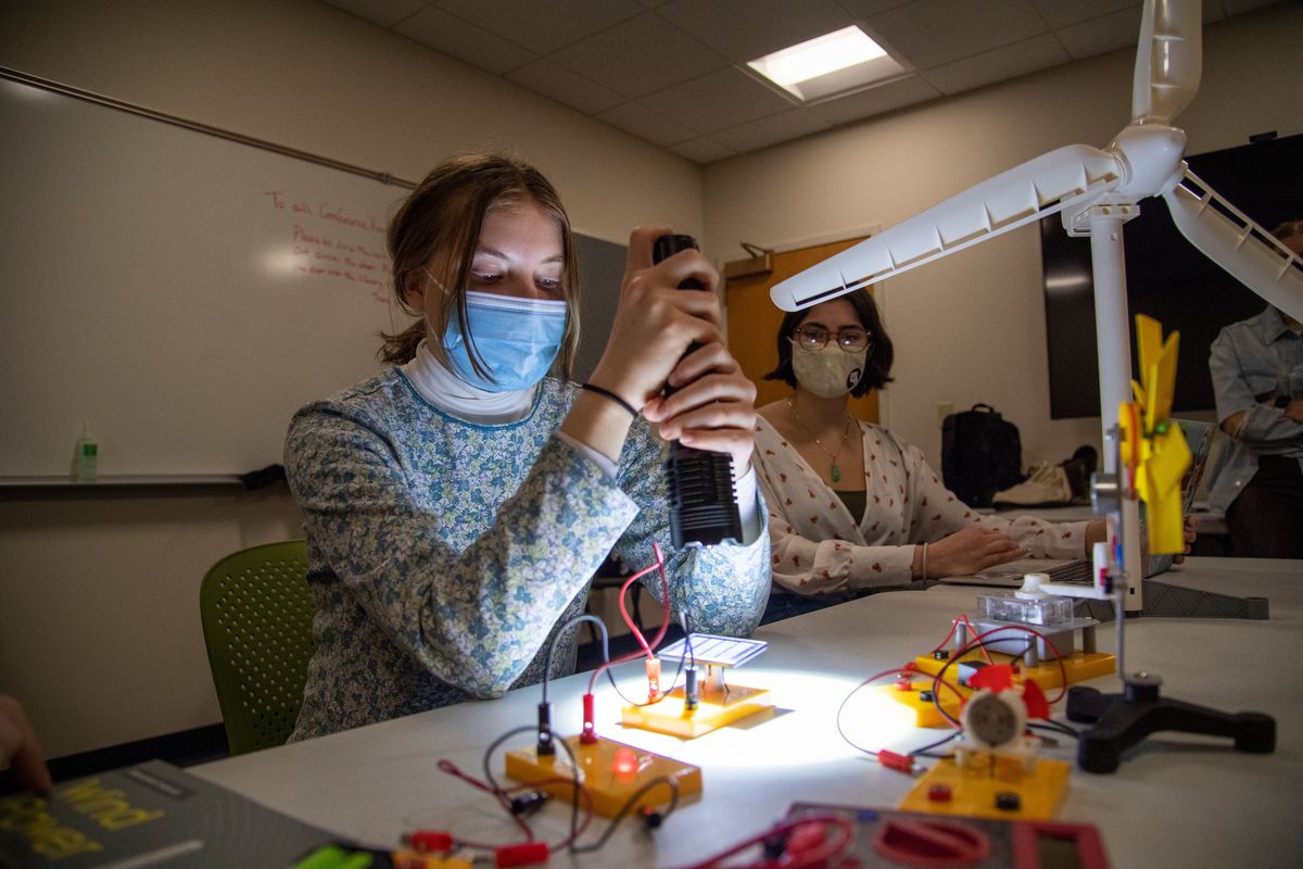 Abby Woodside, left, shines a flashlight on a small solar panel to power up an LED, as Emily Wright looks on. Woodside is testing the science kit the Gonzaga Climate Literacy fellows plan to use to teach elementary students about renewable wind and solar power.  (Jesse Tinsley/The Spokesman-Review)