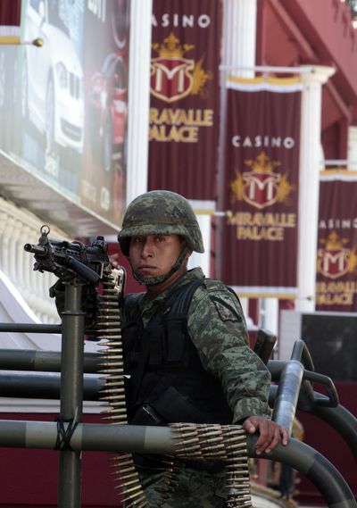 A soldier holds a machine gun outside a casino Saturday in Monterrey, Mexico, where authorities confiscated 1,500 slot machines at 11 casinos. (Associated Press)