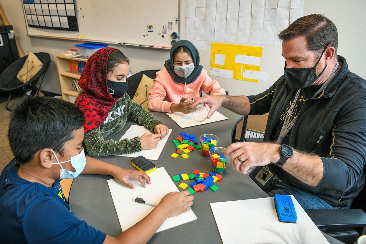 Retired KC-135 pilot Lt. Col. Matt Petro, from Fairchild Air Force Base, teaches fourth-grade students at Linwood Elementary School in Spokane. Here he conducts a math lesson Monday for Robby Typhoon, of the Marshall Islands, left, and Maryam Aslami and Zainab Kohistani, both Afghan refugees.  (DAN PELLE/THE SPOKESMAN-REVIEW)