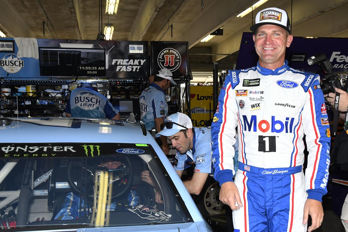 Clint Bowyer smiles as he walks away smiling after talking with Kevin Harvick, in car, in the garage area before practice for a NASCAR Cup series auto race in Fort Worth, Texas, Friday, April 6, 2018. (Larry Papke / Associated Press)