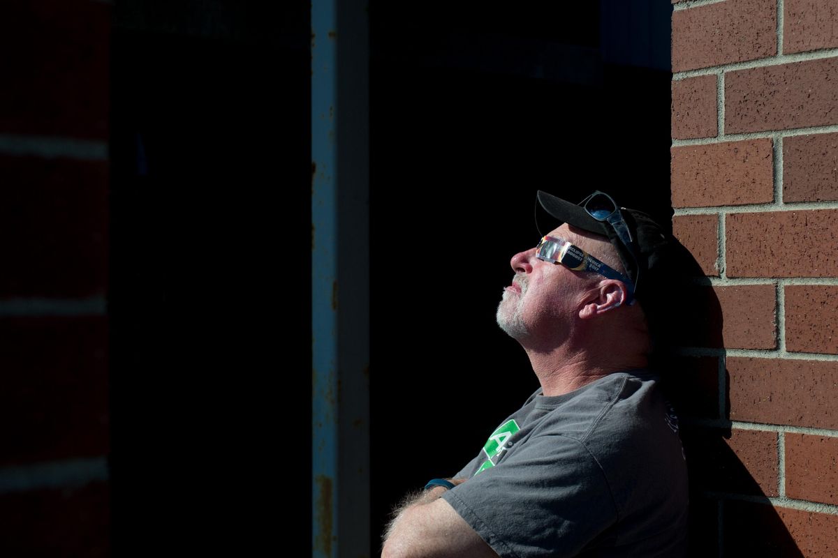 Scott Smith watches a partial solar eclipse during a watch party held by the EWU Astronomy Club on Monday, Aug. 21, 2017, at Roos Field in Cheney, Wash. (Tyler Tjomsland / The Spokesman-Review)