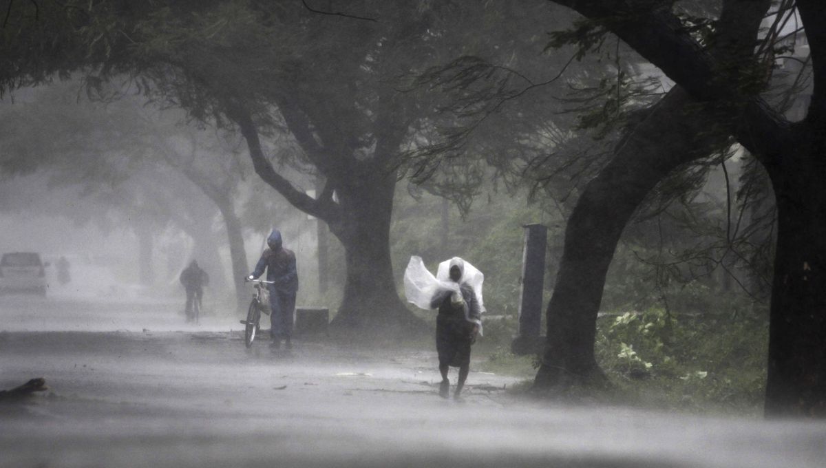 Residents make their way through wind and rain in Ganjam district of eastern India on Saturday. (Associated Press)