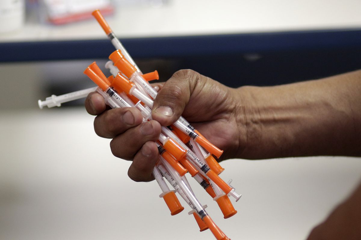 FILE - In this May 6, 2019 photo file photo an injection drug user, deposits used needles into a container at the IDEA exchange, in Miami. National data is incomplete, but available information suggests U.S. drug overdose deaths are on track to reach an all-time high. Addiction experts blame the pandemic, which has left people stressed and isolated, disrupted treatment and recovery programs, and contributed to an increasingly dangerous illicit drug supply.  (Lynne Sladky)