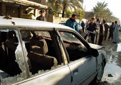 Passers-by look at a shot-out car that had been carrying Iraqis who work on a U.S. military base in Baqouba on Thursday. Insurgents ambushed the vehicle, which was carrying seven people, killing two and wounding four, with one escaping unhurt.
(Associated Press / The Spokesman-Review)