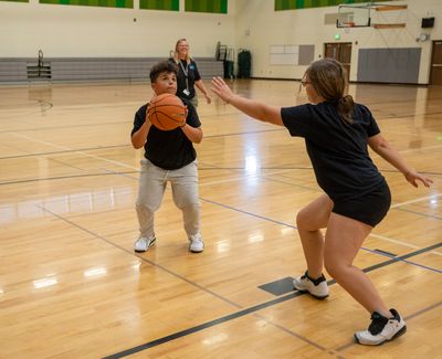 Josiah Hansen, 12, left, prepares to shoot against Zaya Brown, 12, while Audra Godwin watches the action Monday at the first open gym session at Salk Middle School in North Spokane.  (Jesse Tinsley/The Spokesman-Revi)