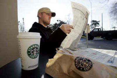 
J.J. Geise reads a paper as he treats himself to coffee and a baked good at a Starbucks coffee shop in Seattle on Jan. 25. Associated Press
 (Associated Press / The Spokesman-Review)