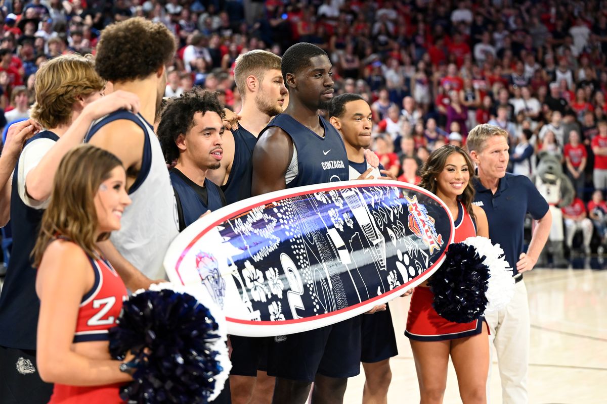 Coach Mark Few (right), Gonzaga players and cheerleaders pose with a surfboard at Kraziness in the Kennel to promote their participation in the Maui Invitational.  (By Jesse Tinsley/The Spokesman-Review)