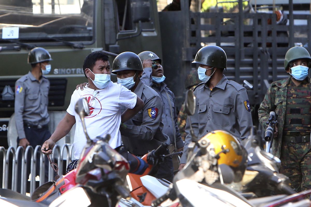 A man is held by police during a crackdown on anti-coup protesters holding a rally in front of the Myanmar Economic Bank in Mandalay, Myanmar on Monday, Feb. 15, 2021. Security forces in Myanmar intensified their crackdown against anti-coup protesters on Monday, seeking to quell the large-scale demonstrations calling for the military junta that seized power earlier this month to reinstate the elected government. (STR)