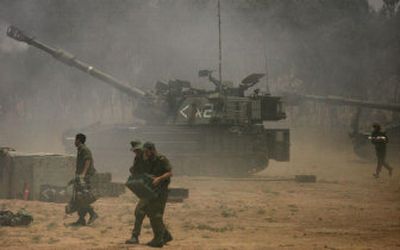 
An Israeli soldier runs to reload An Israeli mobile artillery piece which is firing toward the Gaza Strip at a position near Kibbutz Nahal Oz, just outside the northern Gaza Strip, on Thursday. 
 (Associated Press / The Spokesman-Review)
