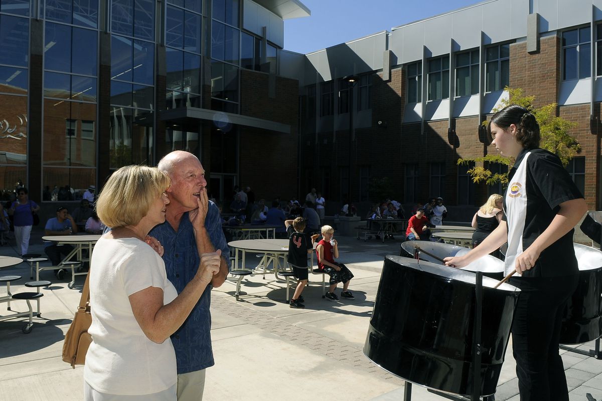 Gayle and Denny Livengood peer over the shoulder of Rogers High School Steel Drum Band member Hanna Pope as they locate the names of Gayle, their two sons and grandson on the Wall of Remembrance for alumni during the school’s reopening Saturday. (The Spokesman-Review)