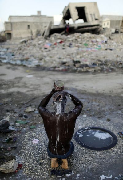 A man bathes with water from a puddle in a street of Port-au-Prince, Haiti, on Monday. Health officials fear that recent flooding could worsen a cholera outbreak.  (Associated Press)