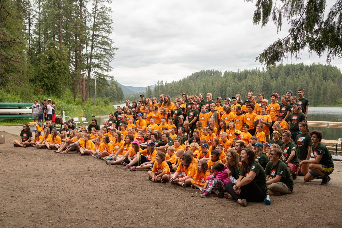 Campers and counselors of Camp Goodtimes pose for a group photo in front of Fan Lake at YMCA Camp Reed on July 10, 2018, Camp Goodtimes is for children who have experienced cancer, and the children invite a friend each to experience a week of fun activities with them. (Libby Kamrowski / The Spokesman-Review)