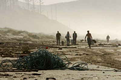 
People comb a stretch of beach Tuesday near Tillamook Bay, Ore., after a crabbing boat broke up in rough seas off the coast before dawn.
 (Associated Press / The Spokesman-Review)