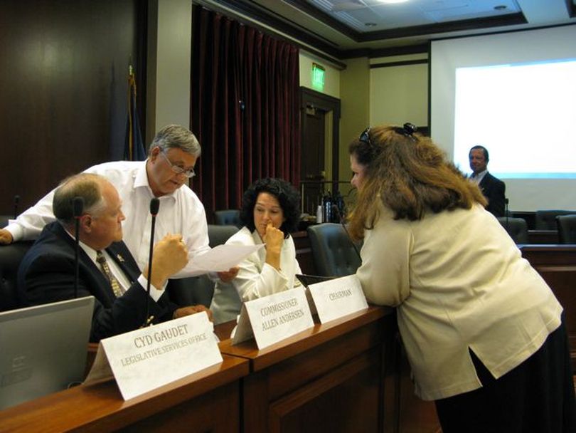 Idaho redistricting commissioners, from left, Allen Andersen, Evan Frasure, Julie Kane and Lorna Finman huddle over a map just after adjourning their commission meeting on Tuesday afternoon; in the background at right is Commissioner George Moses. (Betsy Russell)