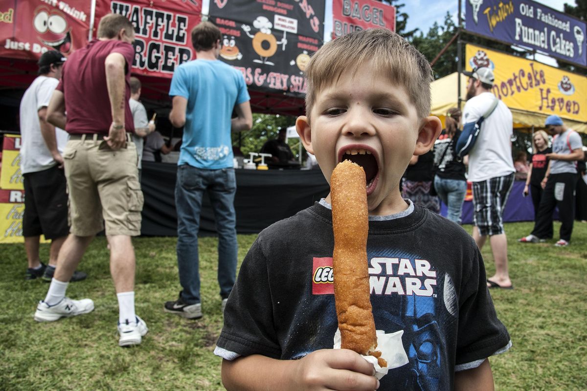 Tyler Stenson, 5, devours a giant corn dog during the 37th annual Pig Out in the Park in 2016. (Dan Pelle / The Spokesman-Review)