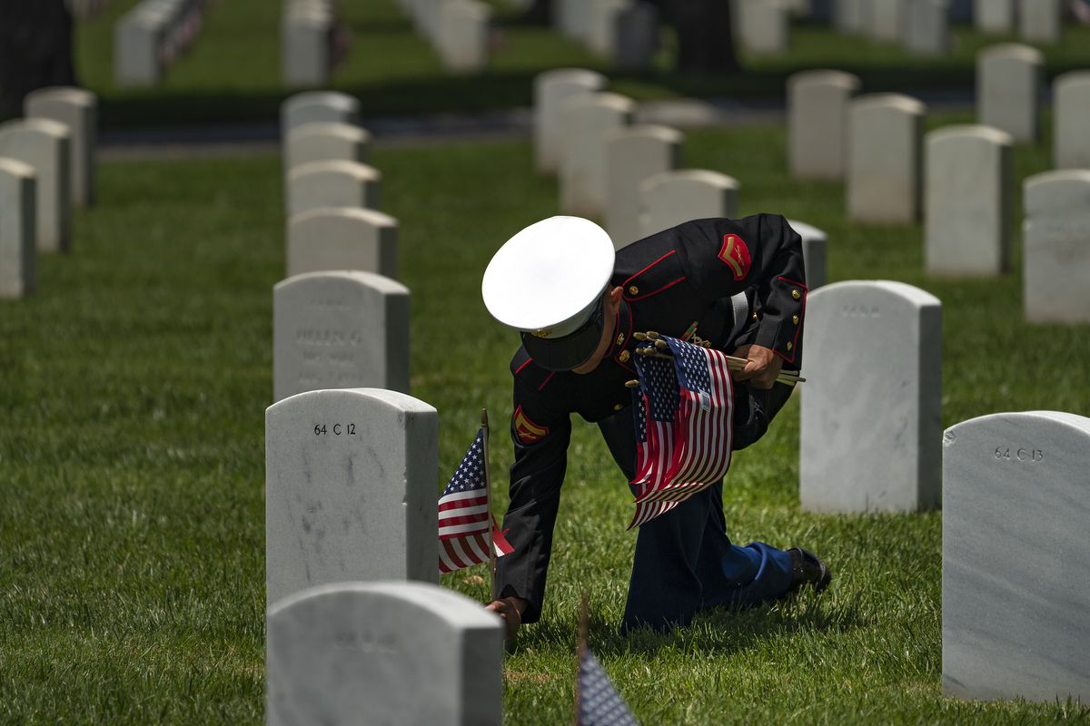 A member of the U.S. Marine Corps, who wants to remain anonymous, honors veterans graves at the Los Angeles National Cemetery in Los Angeles, Monday, May 31, 2021. He has placed American flags for the past 15-years, first as a boy scout, this year as a U.S. Marine.  (Damian Dovarganes)