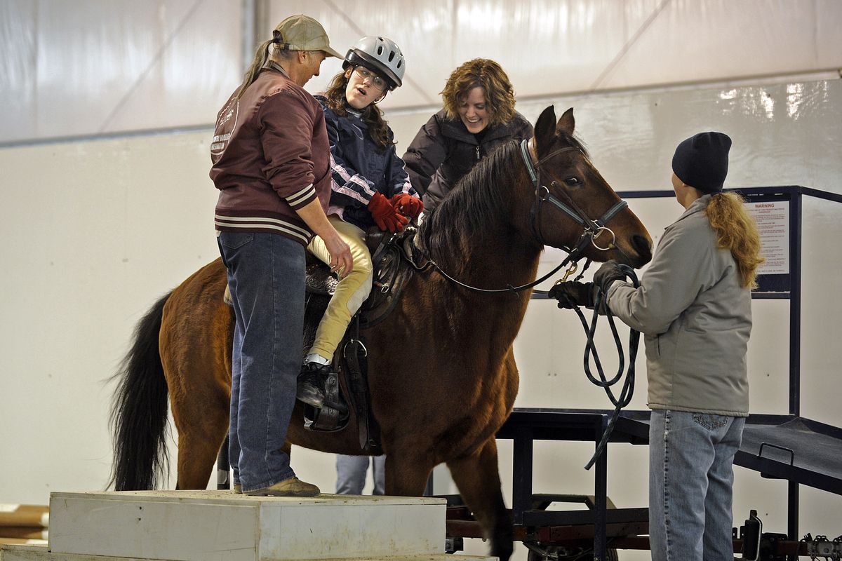 Cyndi Caniglia, rear, steadies Kendyl Caro, in helmet, on Mandy at the loading platform for a ride  Nov. 13. Helping are Donna Carberrry, left, and Megan Buff.