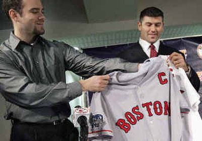 
Catcher Jason Varitek, right, receives a Boston jersey with a 