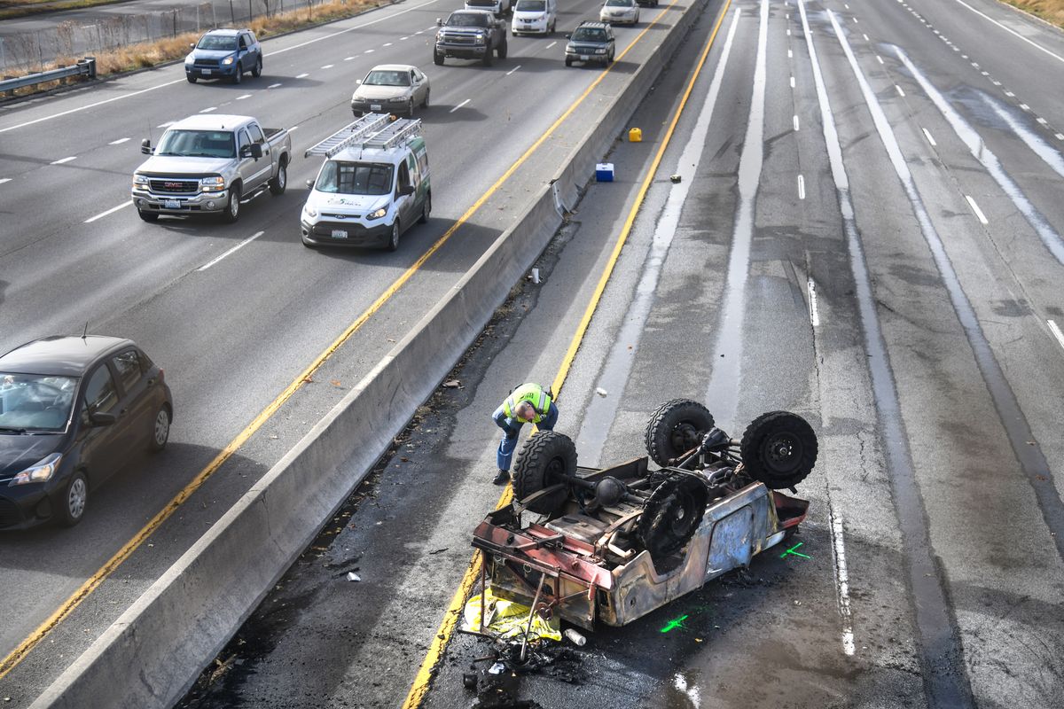 A member of the Washington State Patrol takes a closer look at a fatal crash, Friday on westbound I-90 near Freya Street in Spokane.  (DAN PELLE/THE SPOKESMAN-REVIEW)