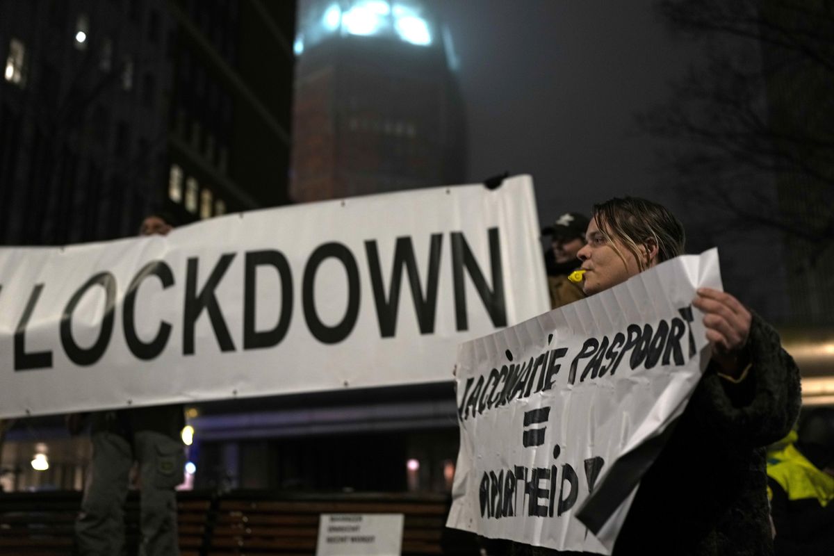 A protestor holds a banner during a small anti-COVID restriction demonstration in the Hague, the Netherlands, Saturday, Dec. 18, 2021. Dutch government ministers are meeting Saturday to discuss advice from a panel of experts who are reportedly advising a toughening of the partial lockdown that is already in place to combat COVID-19. (Peter Dejong)