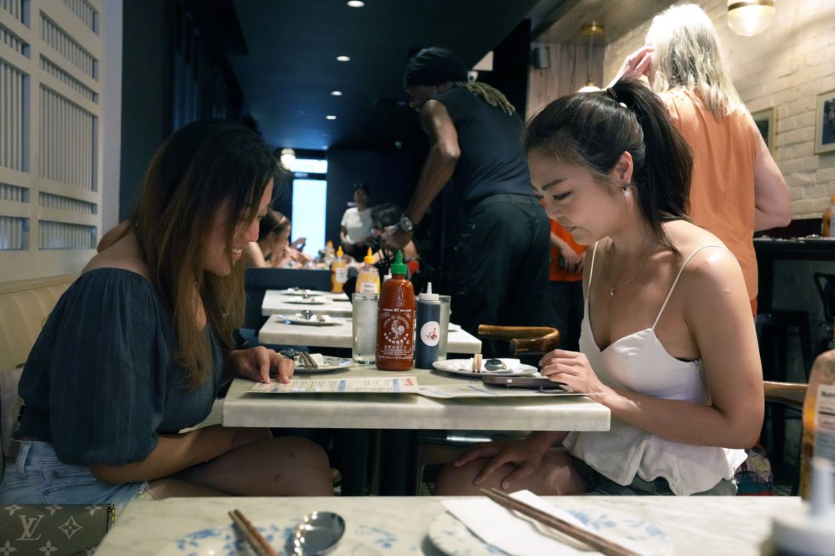 Two guests share a sriracha bottle at Madame Vo, in New York on July 9. Huy Fong Foods is having production issues for the second year in a row, causing some people to pay high prices on eBay.  (MICHELLE V. AGINS/New York Times)