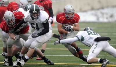Ferris’ Garrett Saiki tries to dart between Skyline’s Jeremy Veilleux, right, and lineman Evan Day in their State 4A semifinal. (Jesse Tinsely / The Spokesman-Review)