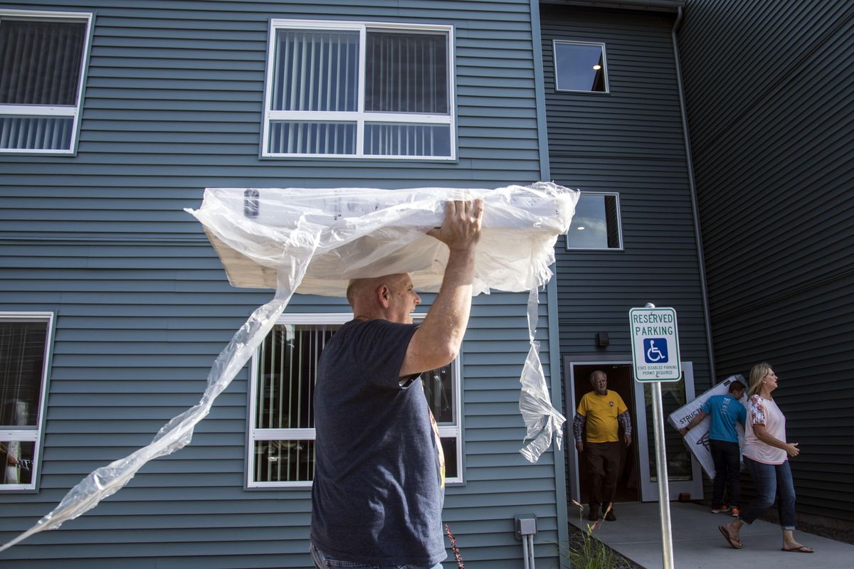 Volunteer Carlos Watkins hauls a bed frame into the Pope Francis Haven House, July 20, 2017, in Spokane Valley, Wash. The Mormon Church donated 200 bed to the Catholic Charities homeless housing project. (Dan Pelle / The Spokesman-Review)