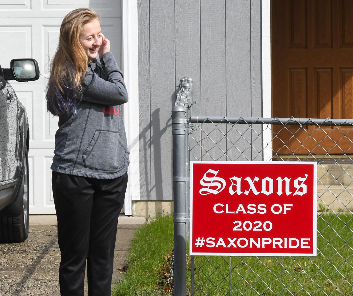 Ferris High School student Maddie Anderson views a sign honoring class seniors placed in her front yard by orchestra instructor Chris Ehrlich, Wednesday, April 15, 2020, in Spokane, Wash. Ferris teachers and staff, along with the the PTG, joined forces to surprise students in the senior class. (Dan Pelle / The Spokesman-Review)