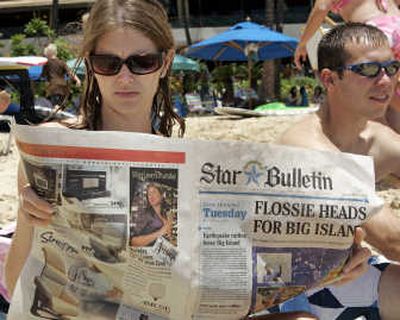 
Tourist Lindsey Young, of Alanson, Mich., reads the Tuesday edition of the Honolulu Star Bulletin while sitting on Waikiki Beach. Oahu is not being affected by Hurricane Flossie.Associated Press
 (Associated Press / The Spokesman-Review)