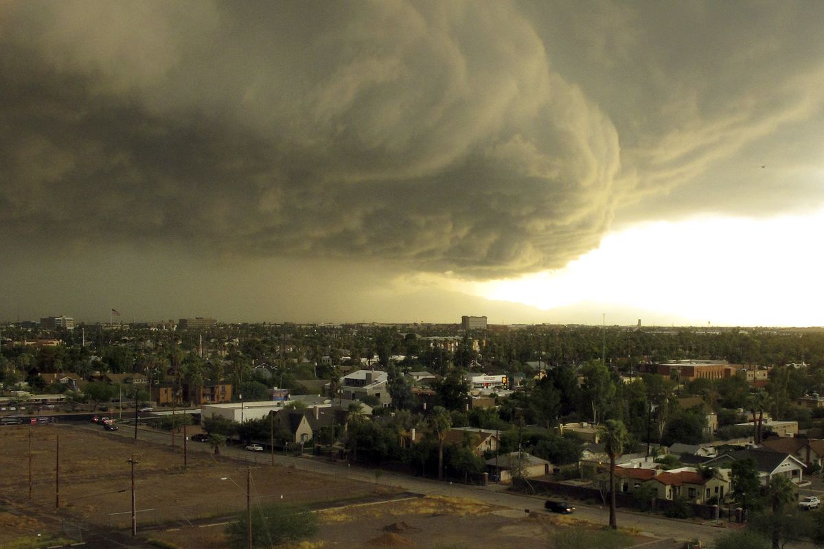 Storm clouds carrying heavy rain move across downtown Phoenix on Tuesday afternoon.  (Associated Press)
