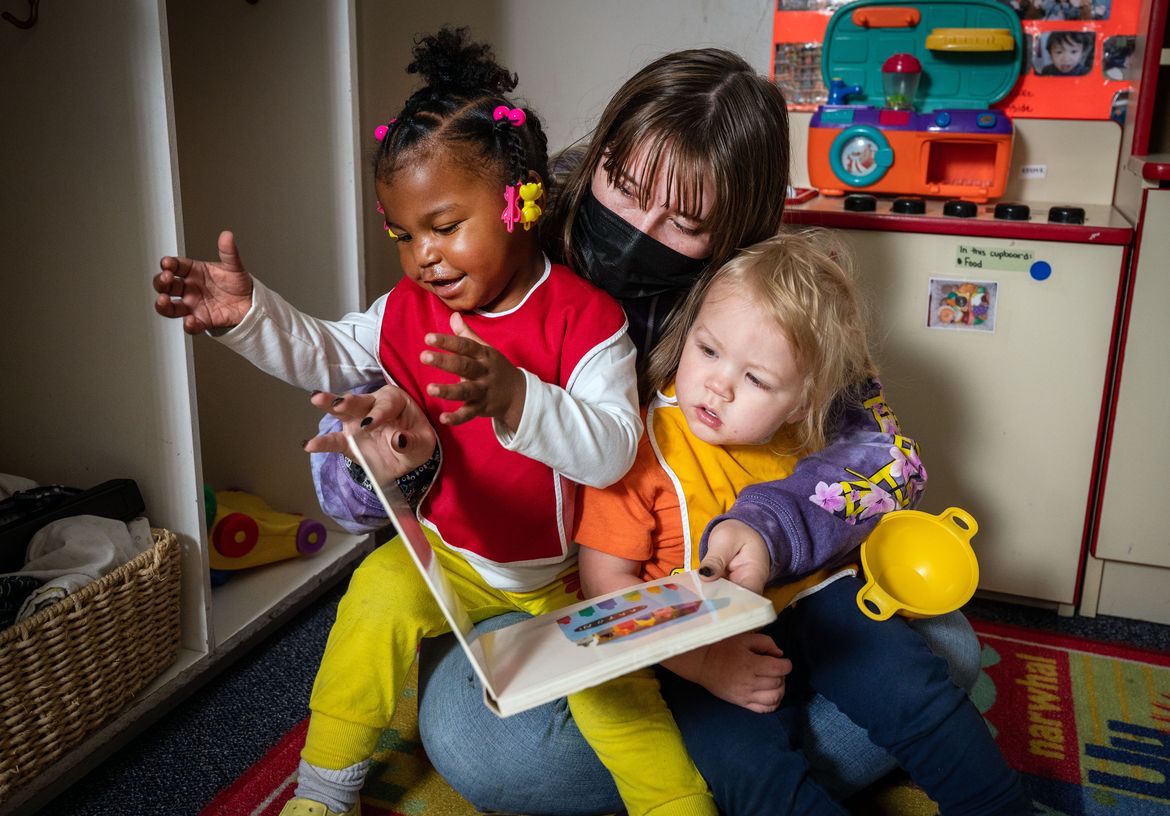 A teacher’s assistant at Spokane Child Development Center in the Spokane Valley reads to two children.