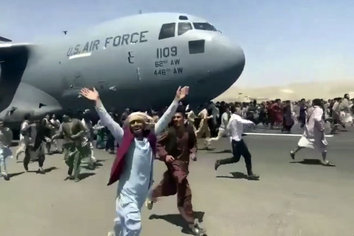 Hundreds of people run alongside a U.S. Air Force C-17 transport plane as it moves down a runway of the international airport, in Kabul, Afghanistan, Monday, Aug.16. 2021. Thousands of Afghans have rushed onto the tarmac of Kabul’s international airport, some so desperate to escape the Taliban capture of their country that they held onto an American military jet as it took off and plunged to death.  (HONS)