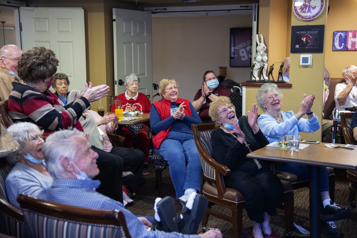 Residents of Touchmark, a retirement community on Spokane’s South Hill, cheer the player introductions Monday before the national championship game in The Clock, the sports bar inside the retirement center.  (Jesse Tinsley/THE SPOKESMAN-REVIEW)