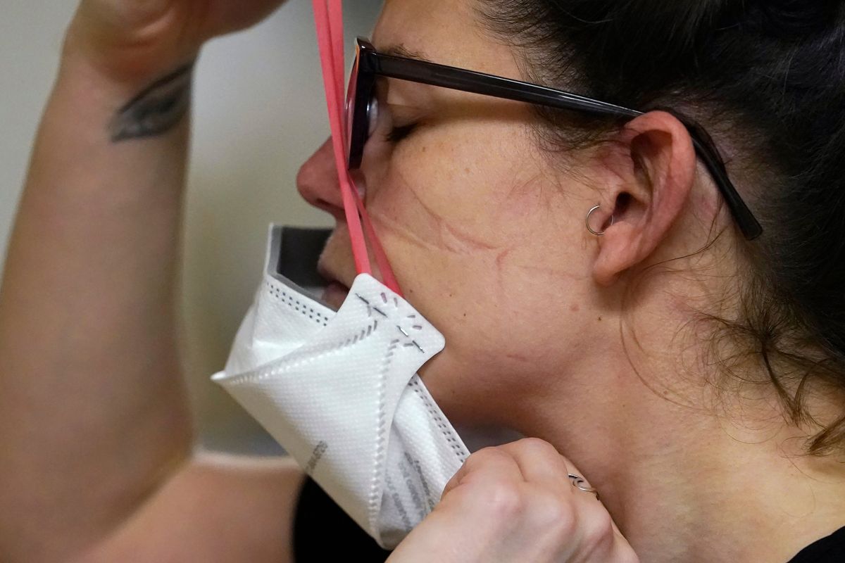 Registered nurse Jessalynn Dest pulls on a new N95 mask after leaving a COVID-19 patient room on Jan. 14 in the acute care unit of Harborview Medical Center in Seattle.  (Elaine Thompson)