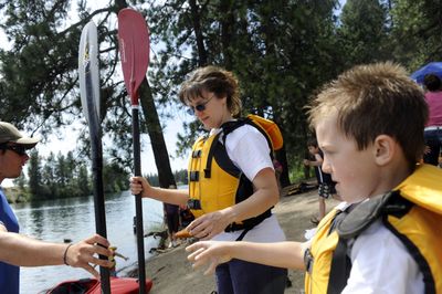 Jennifer Barker, center, and son Ian Barker, 7, get kayak paddles from volunteer Caleb Campbell at Sekani Adventure Day on Saturday. It was a first time for the Barkers to paddle together, and they were able to try rafting, canoeing and kayaking in an hour’s time. The event was put on by the Spokane Parks and Recreation Department at Camp Sekani, a natural area along Upriver Drive. (PHOTOS BY JESSE TINSLEY / The Spokesman-Review)