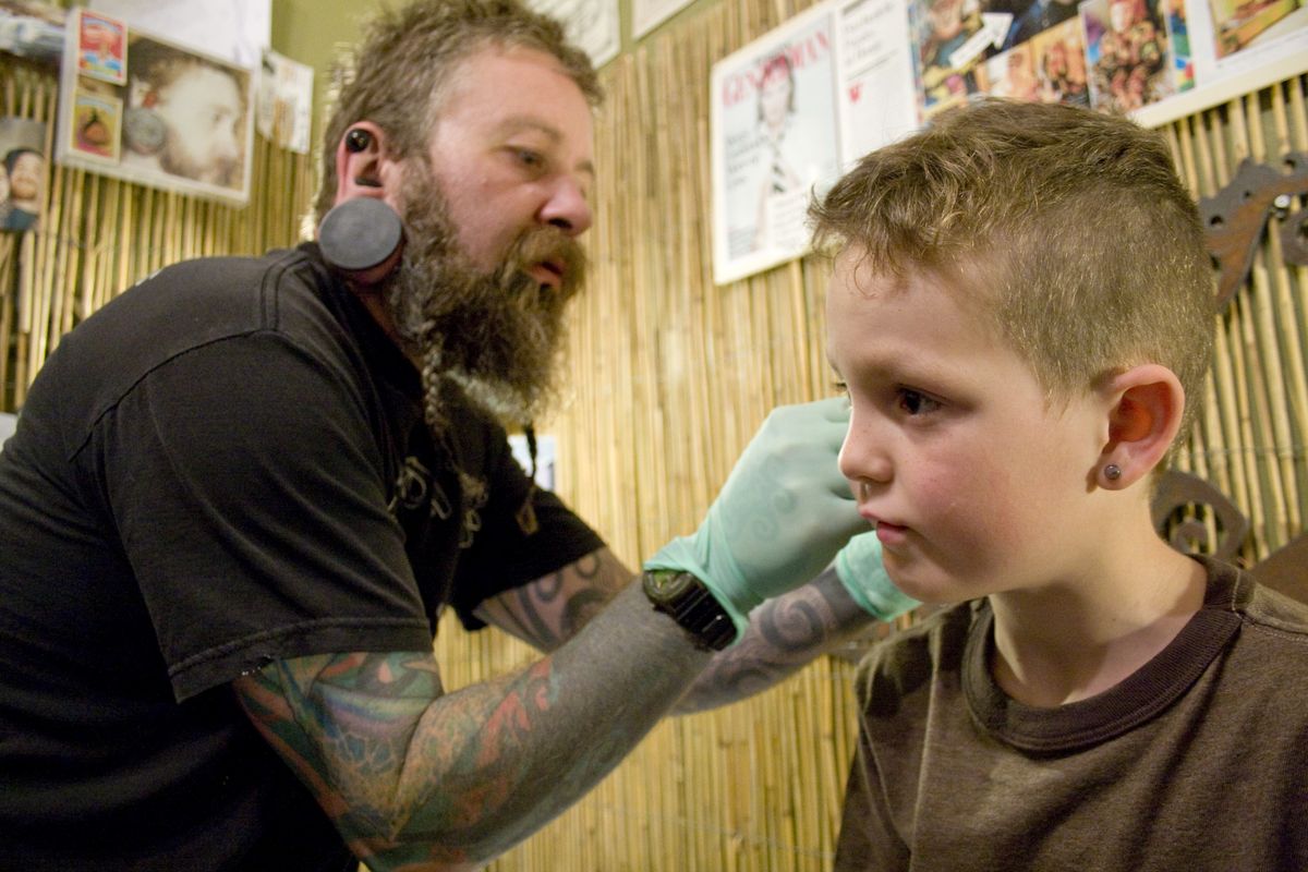 Blake Perlingieri measures Finn Logan, 6, for a slightly larger earplug size at Nomad Precision Body Adornment and Tribal Museum in Portland in June. (Associated Press)