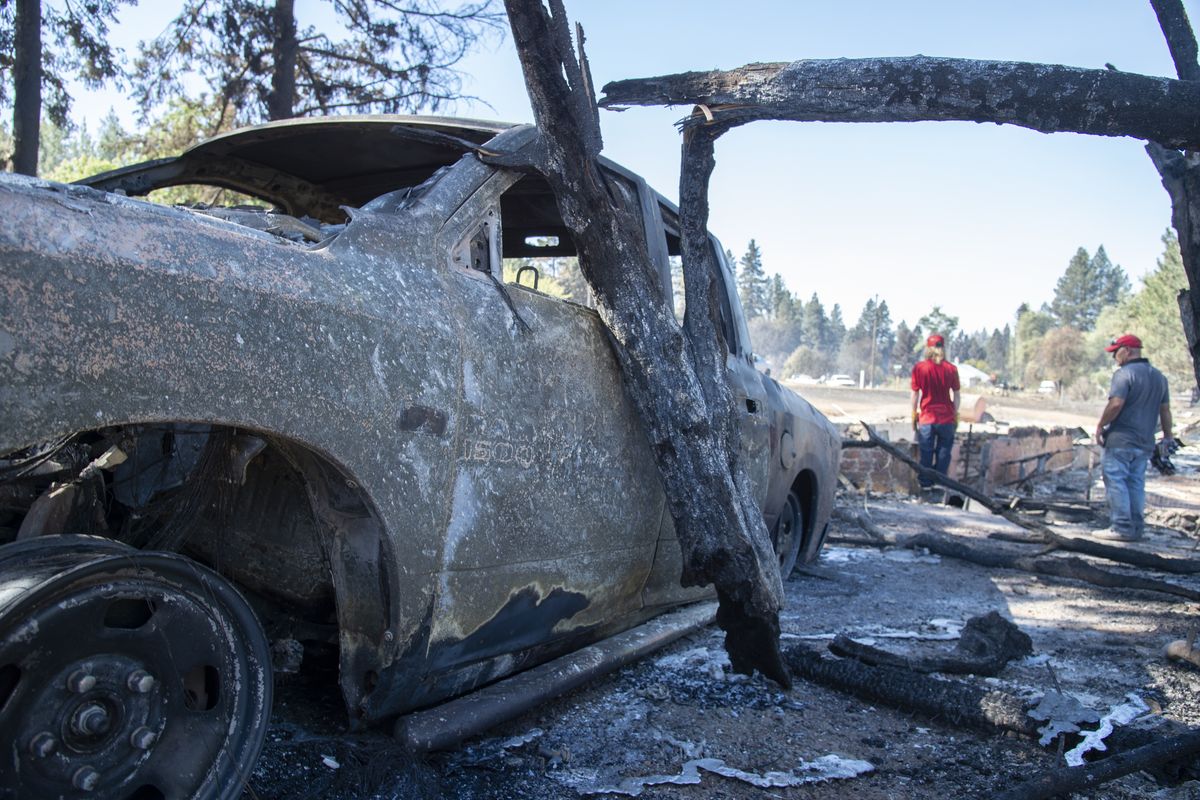 Shawn Thornton, right, and son Chris Thornton look over the rubble of their burned home and garage, including his work truck, left, on Sept. 8 in Malden, Wash., the day after a fast-moving wildfire swept through the tiny town west of Rosalia. Shawn and Shannon weren’t home at the time, but son Cody was and managed to get their dog and a few belongings before leaving just minutes before the flames swept through, destroying their home, garage and multiple vehicles.  (Jesse Tinsley/The Spokesman-Review)