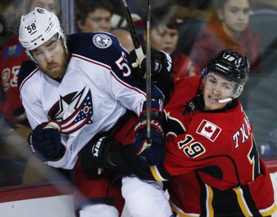 Columbus Blue Jackets' David Savard, left, is checked by Calgary Flames' Matthew Tkachuk during the third period. The Blue Jackets won 4-1 to earn their eighth straight win. (Jeff McIntosh / Associated Press)