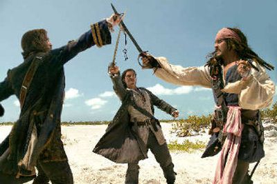 From left, Jack Davenport, Orlando Bloom and Johnny Depp draw swords on the beach in a scene from
