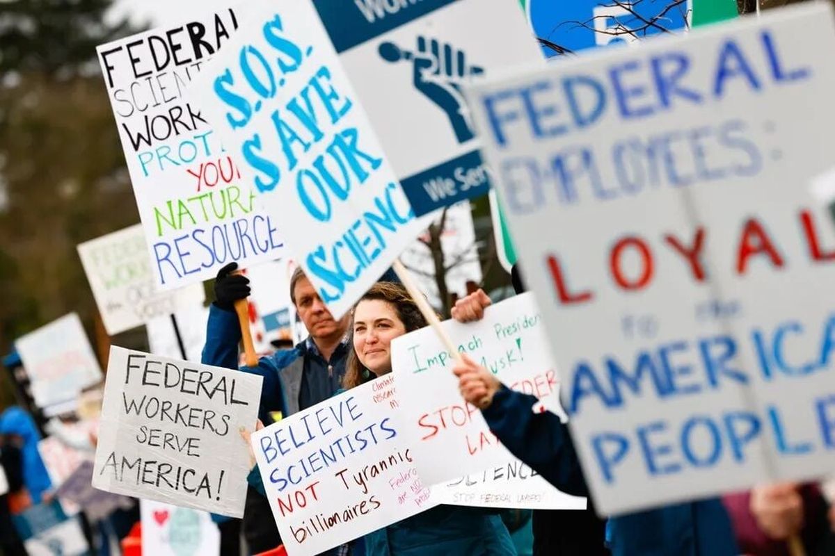 Molly McCormley, center, a marine mammal scientist at the University of Washington, and Morgan Bond, a NOAA fisheries scientist in the watershed program, join a rally on Wednesday outside the NOAA offices in Seattle to protest President Donald Trump’s mass layoff of federal workers. (Karen Ducey/Seattle Times)