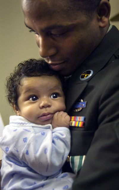 
Spc. Alexis Love holds his 3-month-old son Xavier on Thursday after being honored for service in Iraq. 
 (Holly Pickett / The Spokesman-Review)