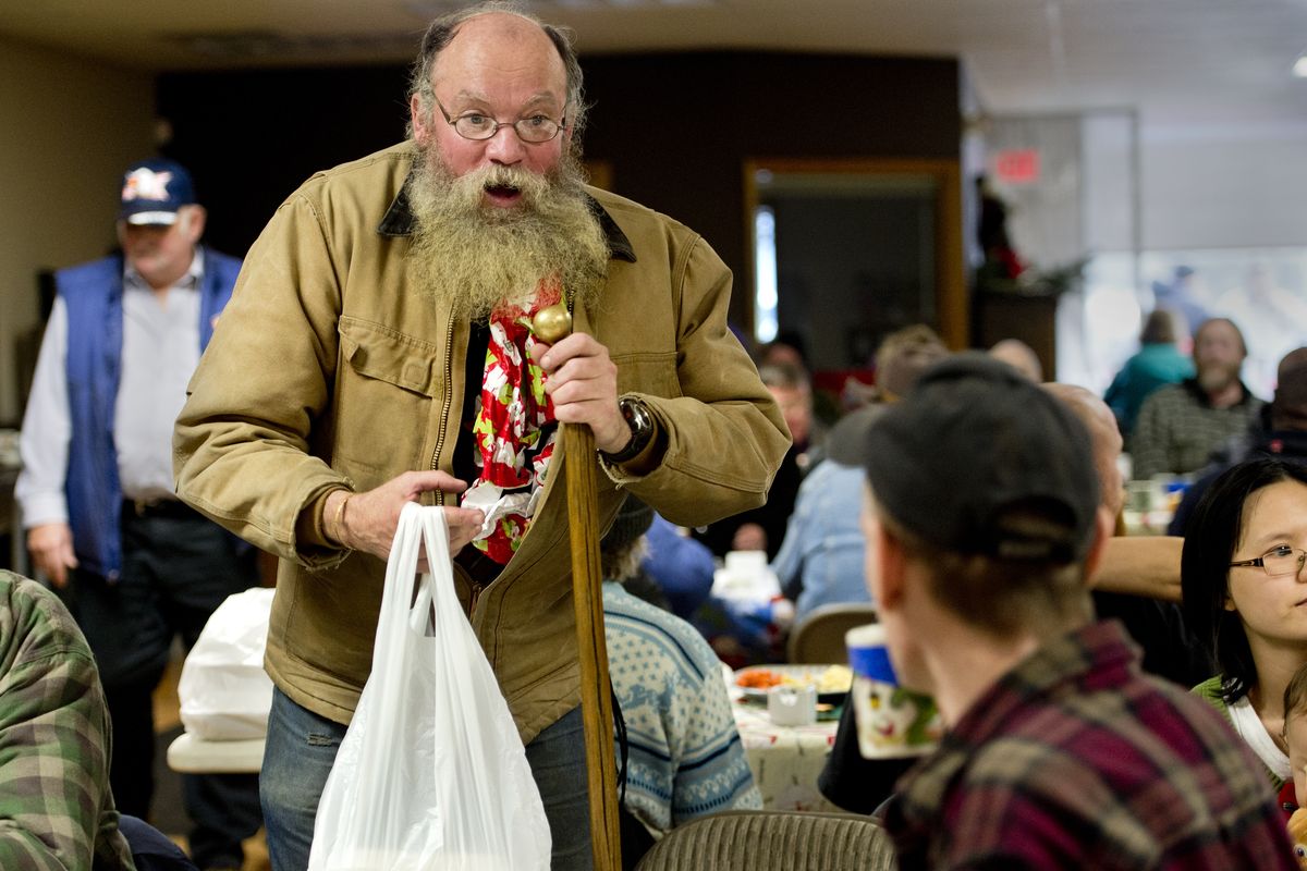 Ivan Brooks, 55, tucks his Christmas present into his jacket as he chats with diners before he leaves a holiday meal at Mid-City Concerns on Christmas. Brooks was walking earlier in the day in the downtown area when people in a van stopped and offered him the gift. Brooks said it was a warm shirt. Volunteers prepared some 400 meals for the event that was open to everyone. (Dan Pelle)