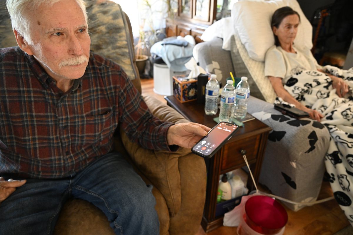 Tim Parkey, left, holds his iPhone last month and listens to yet another telemarketer try to get his information in order to enroll him and his wife Pam in Medicare coverage at their home last month. (Jesse Tinsley/THE SPOKESMAN-REVIEW)