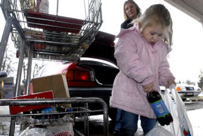 
Laci Chudy,  3, helps her mother, Angie,  load food into their car at the Post Falls Food Bank on Wednesday. The food bank nearly closed in 2006, but a large donation by Super 1 Foods and a  food drive have kept the doors open. Manager Cathy Larson says the food bank is better off than it was a year ago.  
 (Jesse Tinsley / The Spokesman-Review)