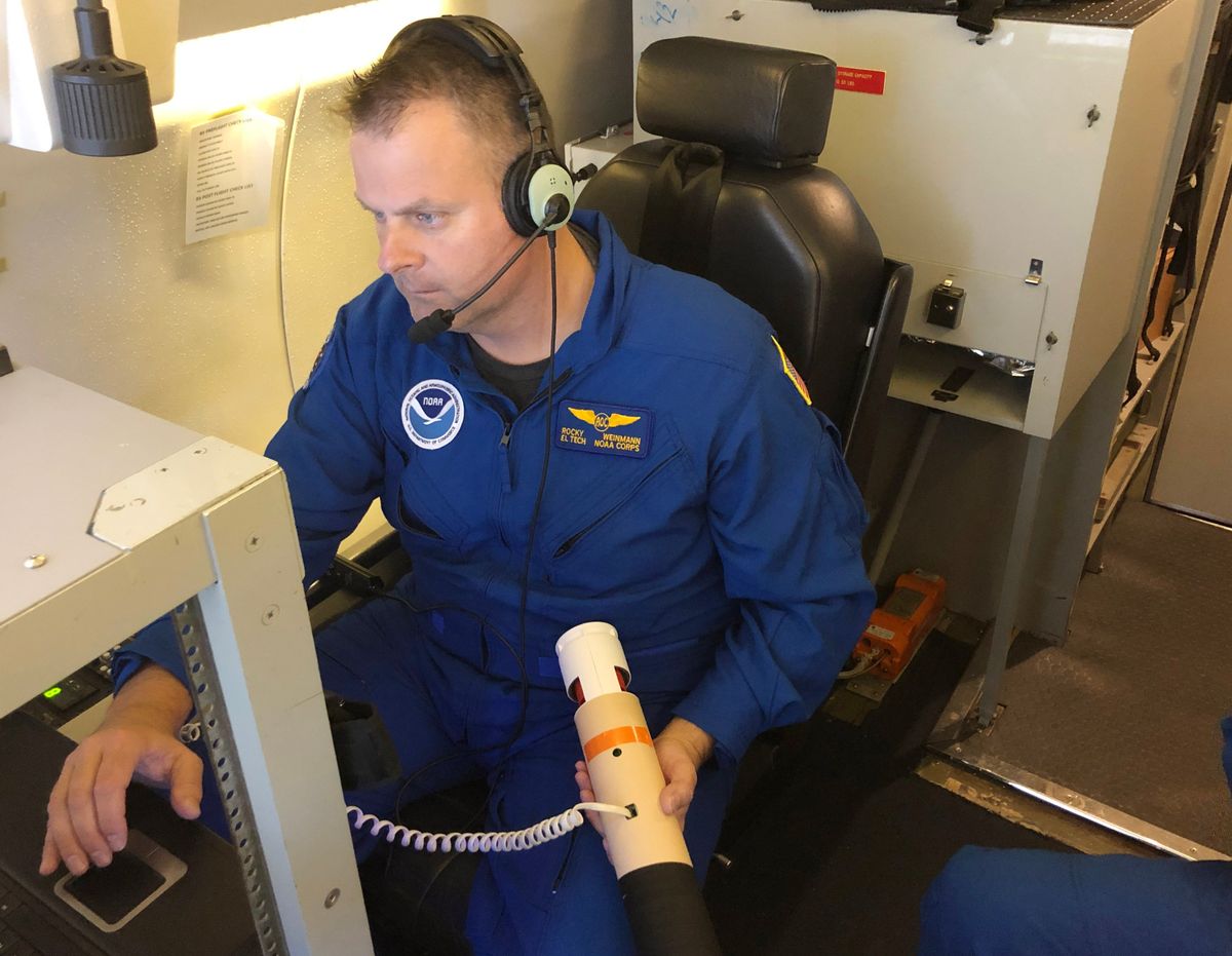 Rocky Weinmann, a drop operator for the National Oceanic and Atmospheric Administration, prepares to deploy a dropsonde from the plane over an atmospheric river.  (Ian James/Los Angeles Times/TNS)