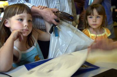 
Six-year-old twins Hannah, left, and Sarah Strafford of Spirit Lake, Idaho, wait with their mother, Wendy, while their  time chips are tested at the trade show. 
 (Holly Pickett / The Spokesman-Review)