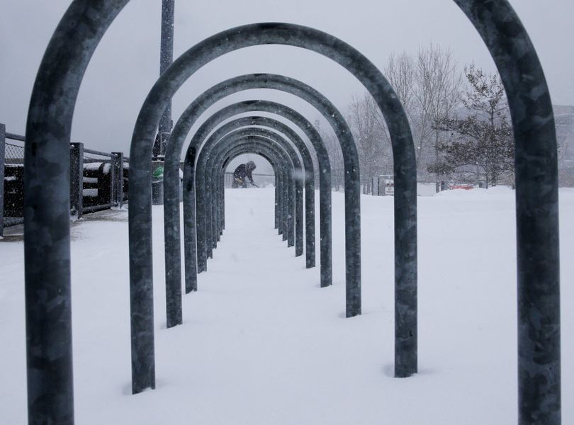 A man, seen through a bicycle rack, shovels snow in the borough of Brooklyn in New York on Saturday, Jan. 23, 2016.  (AP Photo/Peter Morgan)