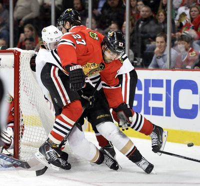 Chicago’s Johnny Oduya, front, and Jonathan Toews knock Anaheim’s Corey Perry off the puck. (Associated Press)